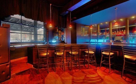 A bar with a lot of stools and a large window