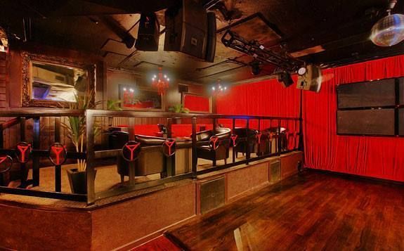 A large empty room with red curtains and a wooden floor.