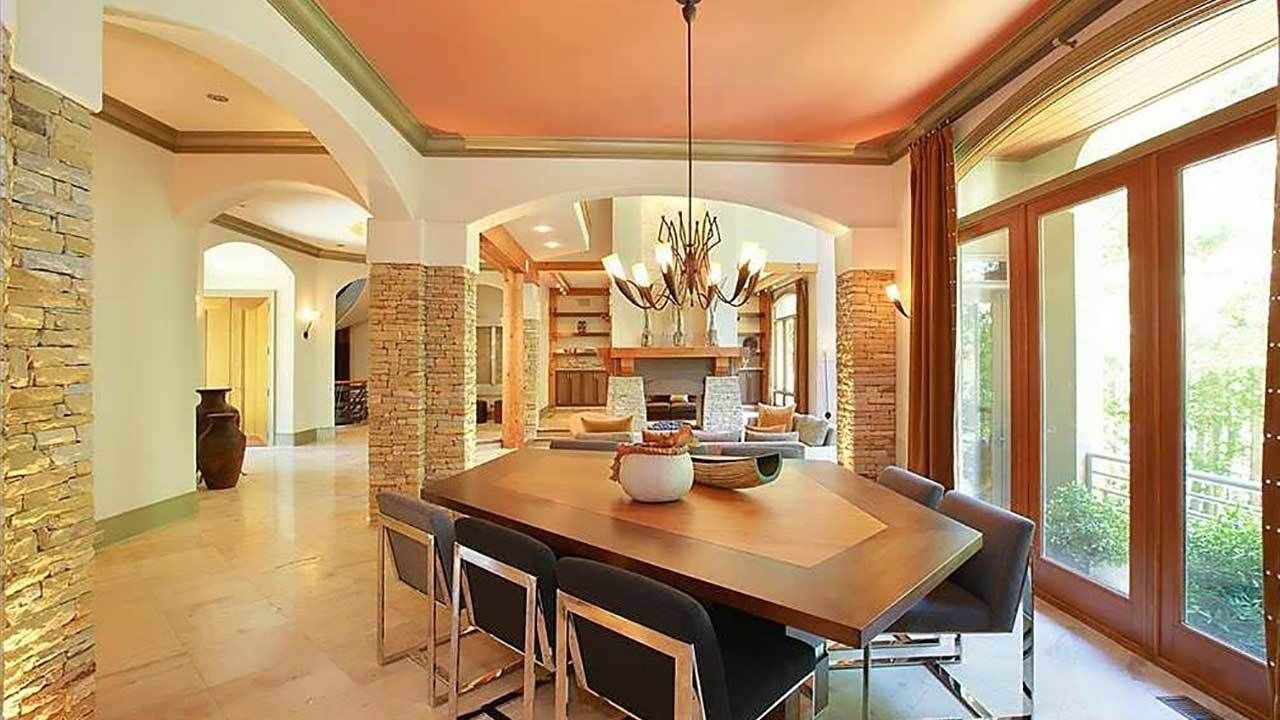 A dining room with a wooden table and chairs and a chandelier hanging from the ceiling.