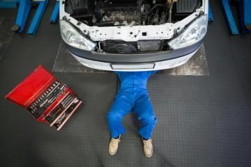 mechanic working under hood of car