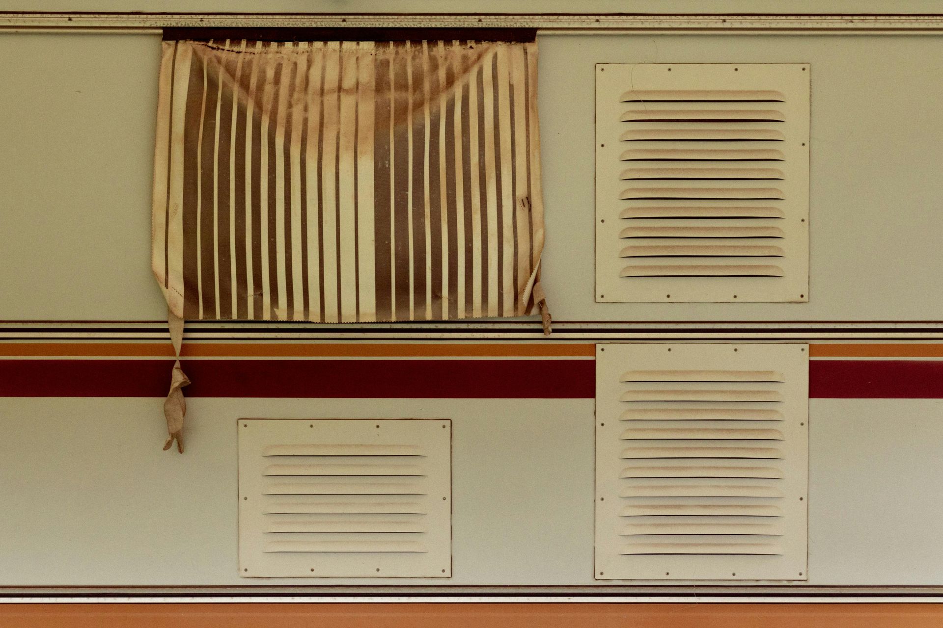 A caravan with a broken curtain and a broken window.