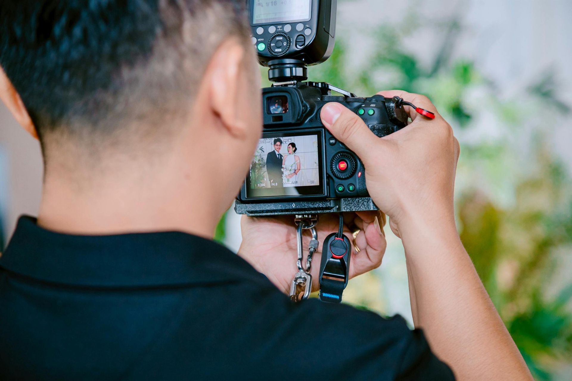 A man is taking a picture of a bride and groom with a camera.