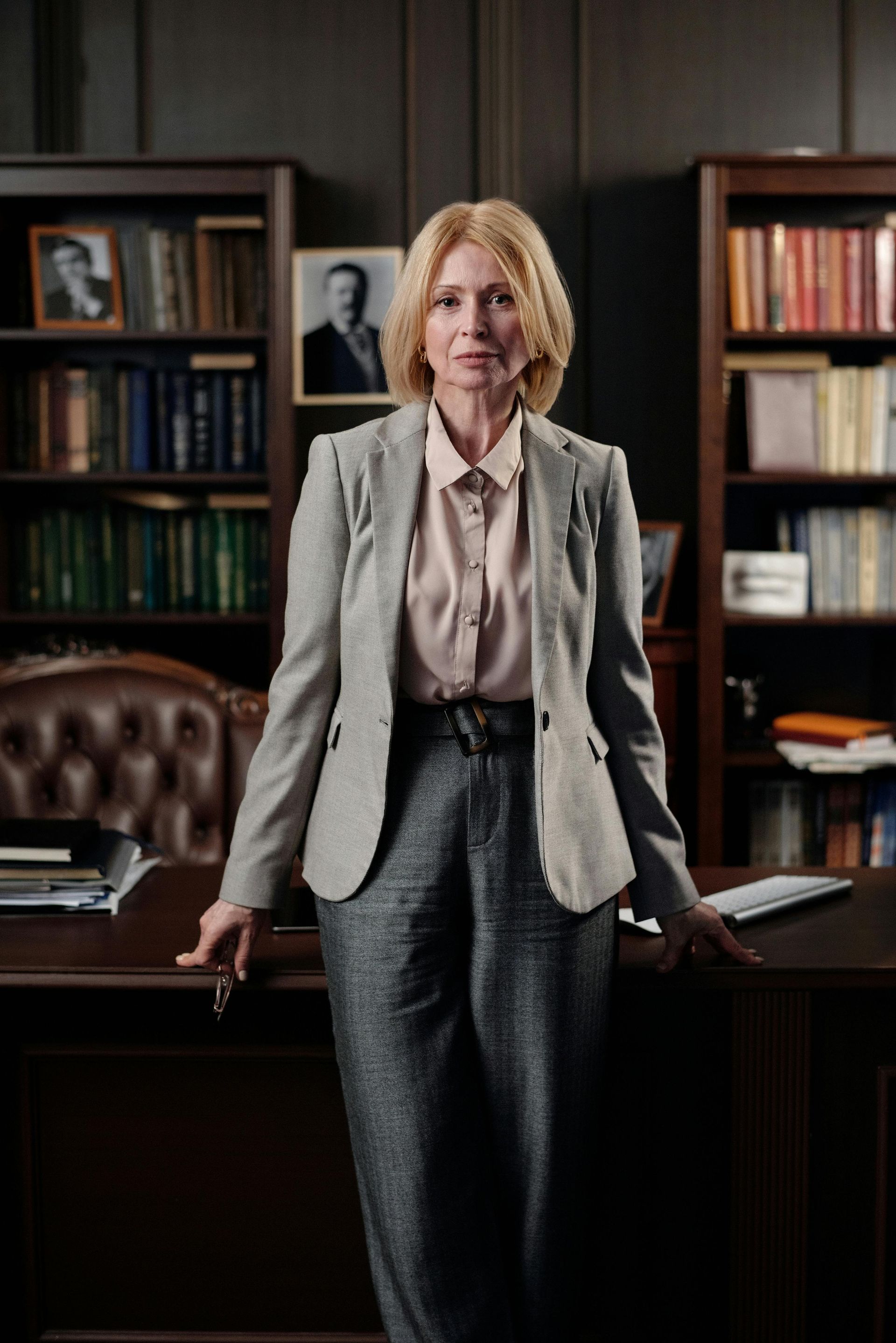 A woman is standing in front of a desk in a library.