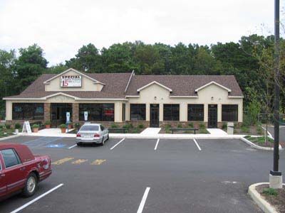 A red car is parked in front of a large building
