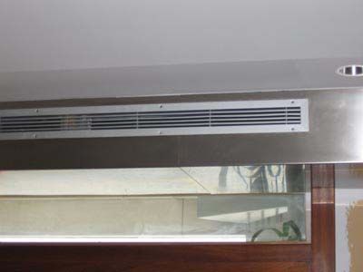 A stainless steel air vent is hanging from the ceiling of a room.