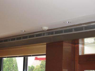 There is a smoke detector on the ceiling of the room.