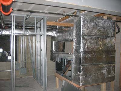 A room with a lot of pipes and ducts hanging from the ceiling.