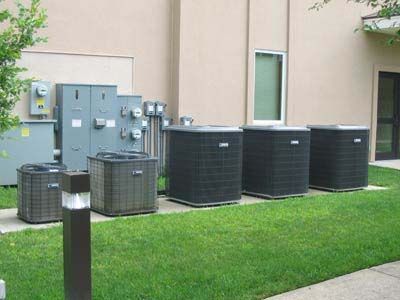 A row of air conditioners are sitting on the side of a building.