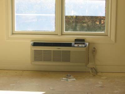 A room with a window and a wall mounted air conditioner.