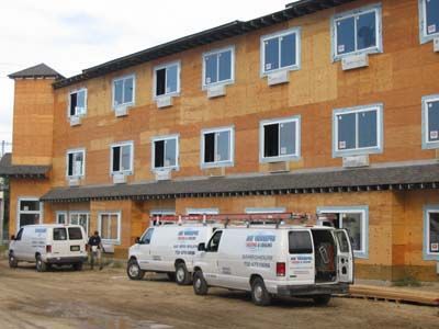 Three vans are parked in front of a building under construction