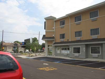 A red car is parked in front of a large building.