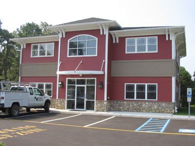 A white truck is parked in front of a red building.