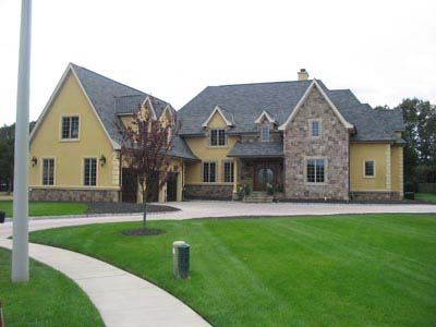 A large yellow house with a stone facade and a gray roof