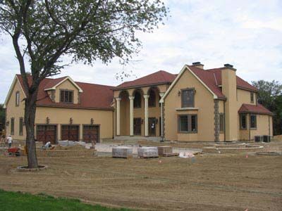 A large house with a red roof is under construction