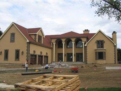 A large house with a red roof is being built