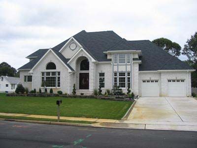 A large white house with a black roof and a driveway