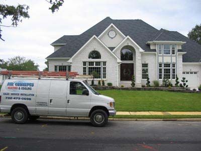 A white van is parked in front of a large white house