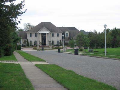 A large white house sits on the corner of a residential street