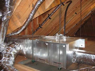 A metal box is sitting in the attic of a house.