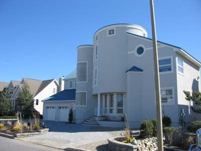 A large white house with a blue roof and stairs
