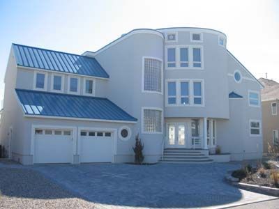 A large white house with a blue roof and two garages