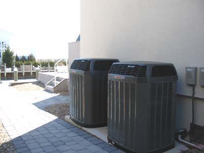 Two air conditioners are sitting on the side of a building.