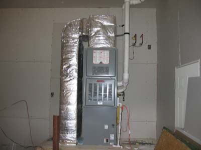 A furnace is sitting in a room next to a pipe.