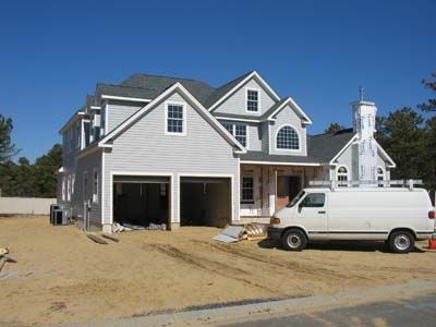A white van is parked in front of a house under construction