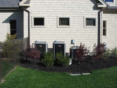 There are two air conditioners on the side of the house.