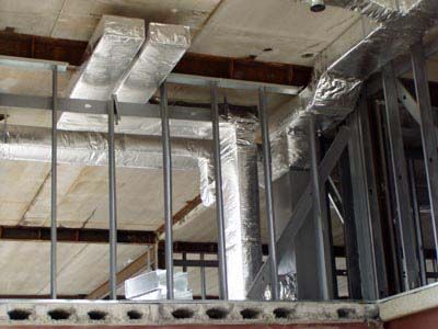 A building under construction with a lot of pipes coming out of the ceiling.