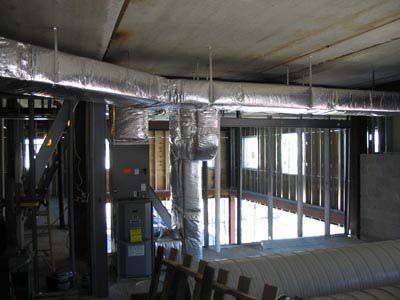 A building under construction with a lot of pipes hanging from the ceiling.