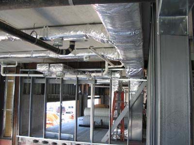 A building under construction with a lot of pipes hanging from the ceiling.