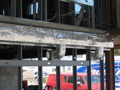A red van is parked in front of a building under construction.