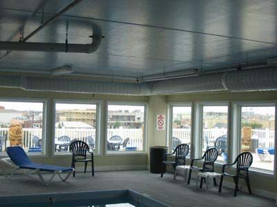 A large indoor swimming pool with chairs and lounge chairs around it.