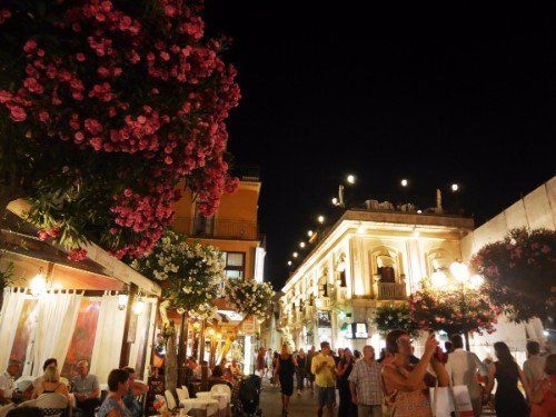 delle persone sedute al tavolo all'esterno e altri mentre passeggiano