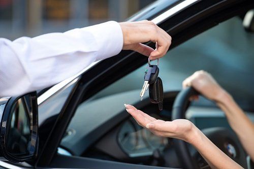 una mano che consegna delle chiavi in una mano di una donna in un'auto