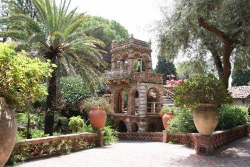 un piccolo monumento in un giardino con alberi e palme