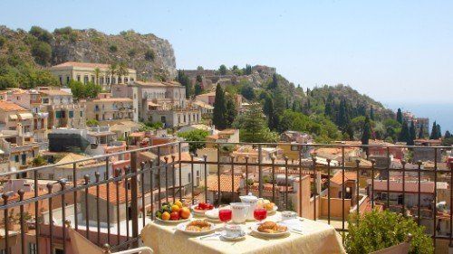 un tavolo apparecchiato in una terrazza con vista di una cittadina e delle colline