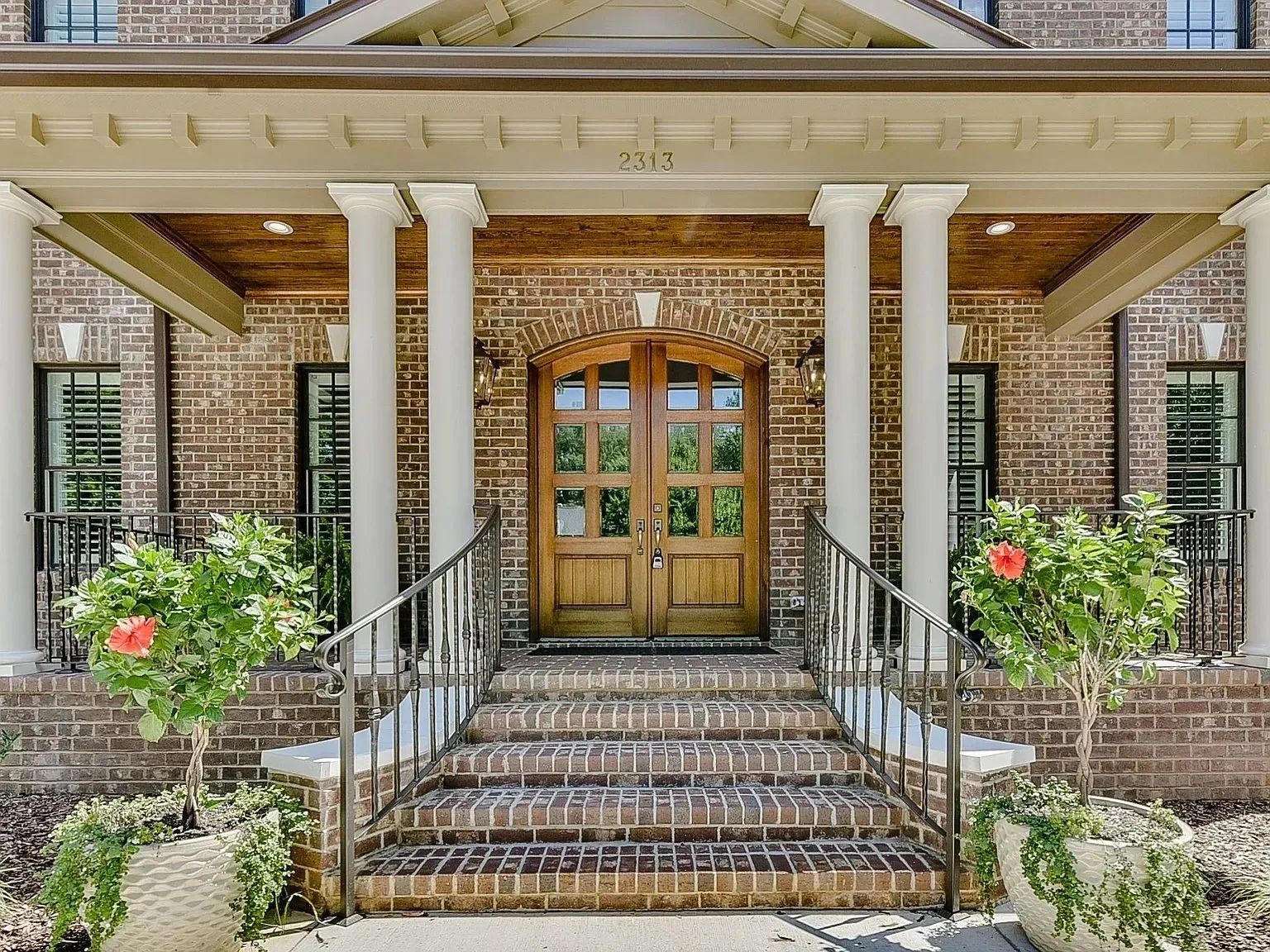 A large brick house with a porch and stairs leading to the front door.