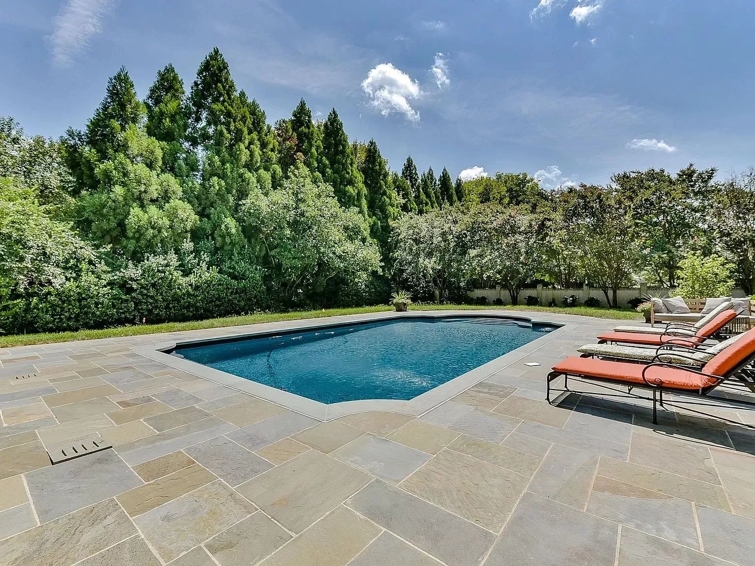 A large swimming pool surrounded by chairs and trees