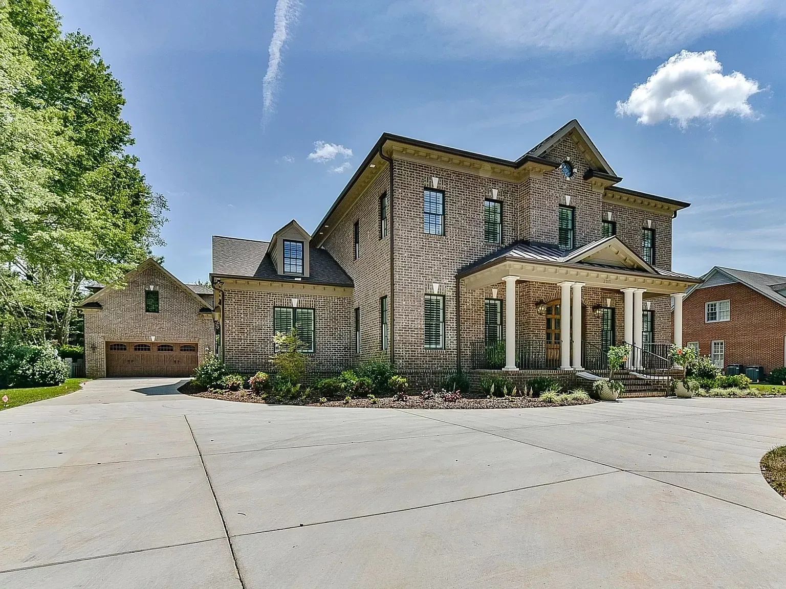 A large brick house with a large driveway in front of it.