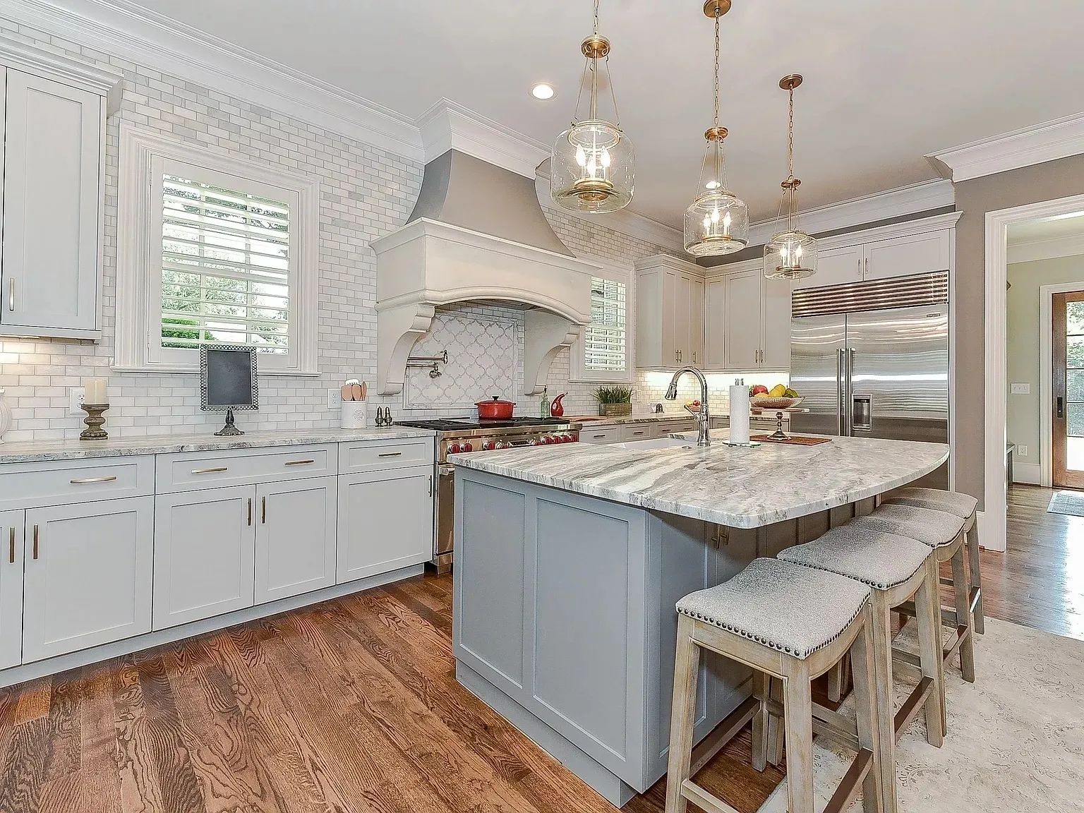 A kitchen with white cabinets , granite counter tops , stainless steel appliances and a large island.