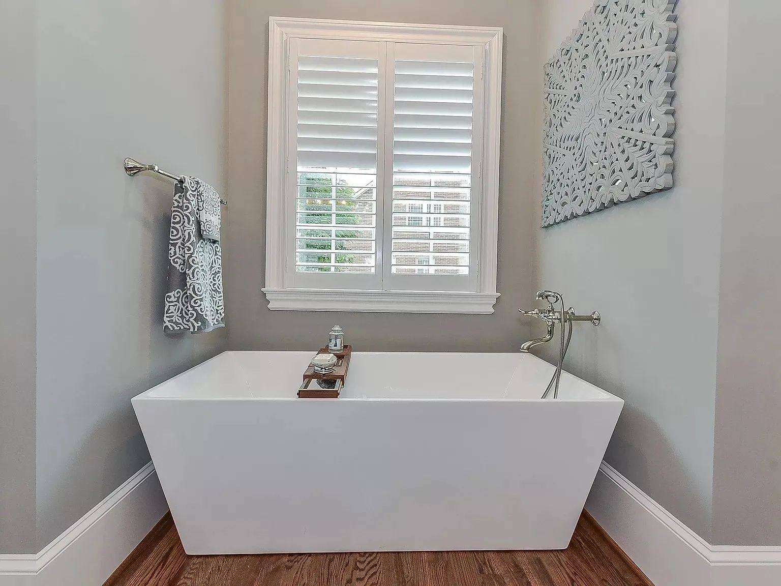 A bathroom with a tub and a window with shutters.