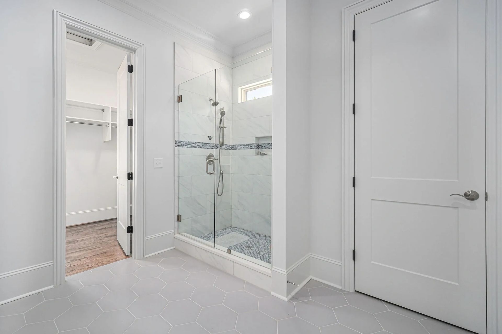 A bathroom with a walk in shower and a closet.