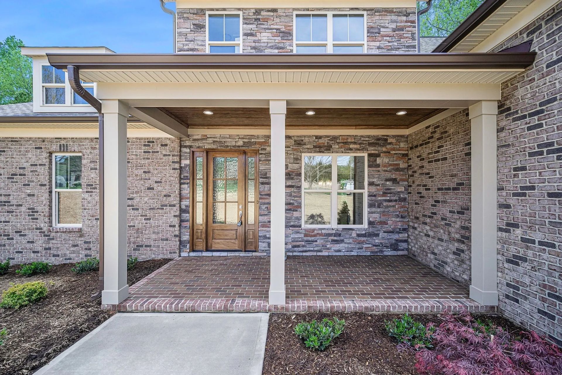 The front of a brick house with a porch and a wooden door.