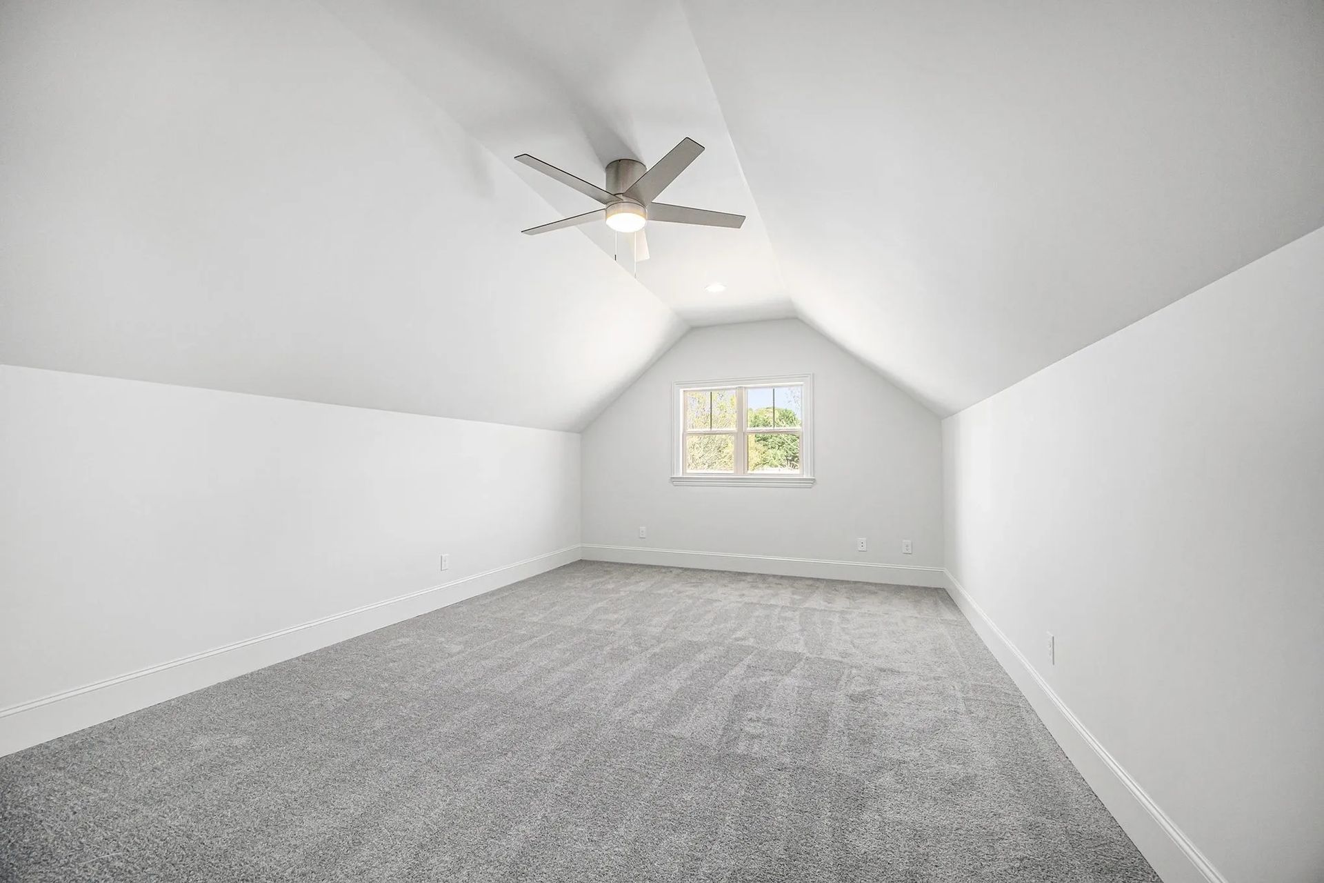 An empty room with a ceiling fan and a window.