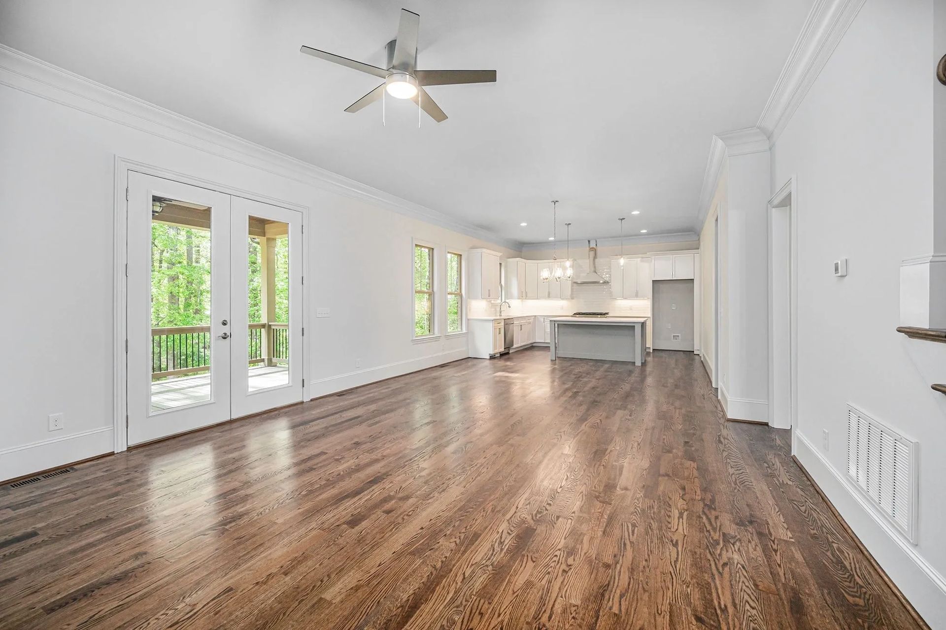 An empty living room with hardwood floors and a ceiling fan.