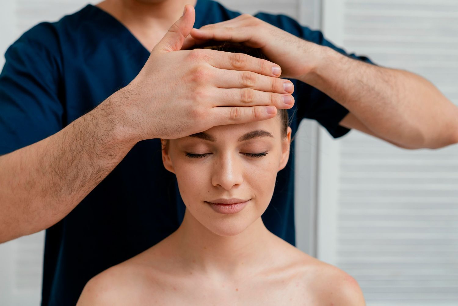 A man is giving a woman a head massage with his hands.