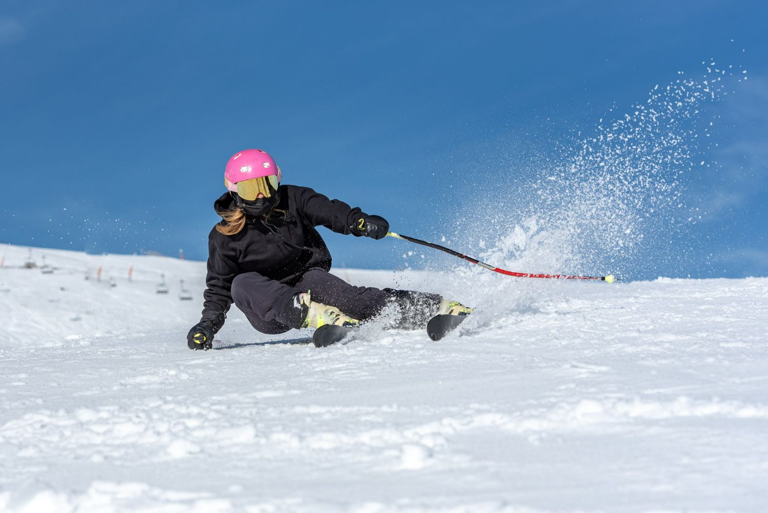 A woman is skiing down a snow covered slope.