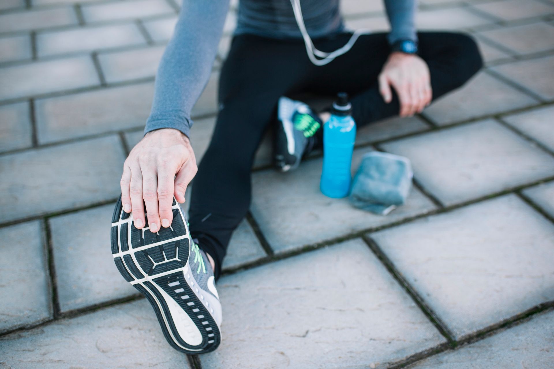 A person is sitting on the ground stretching their legs.